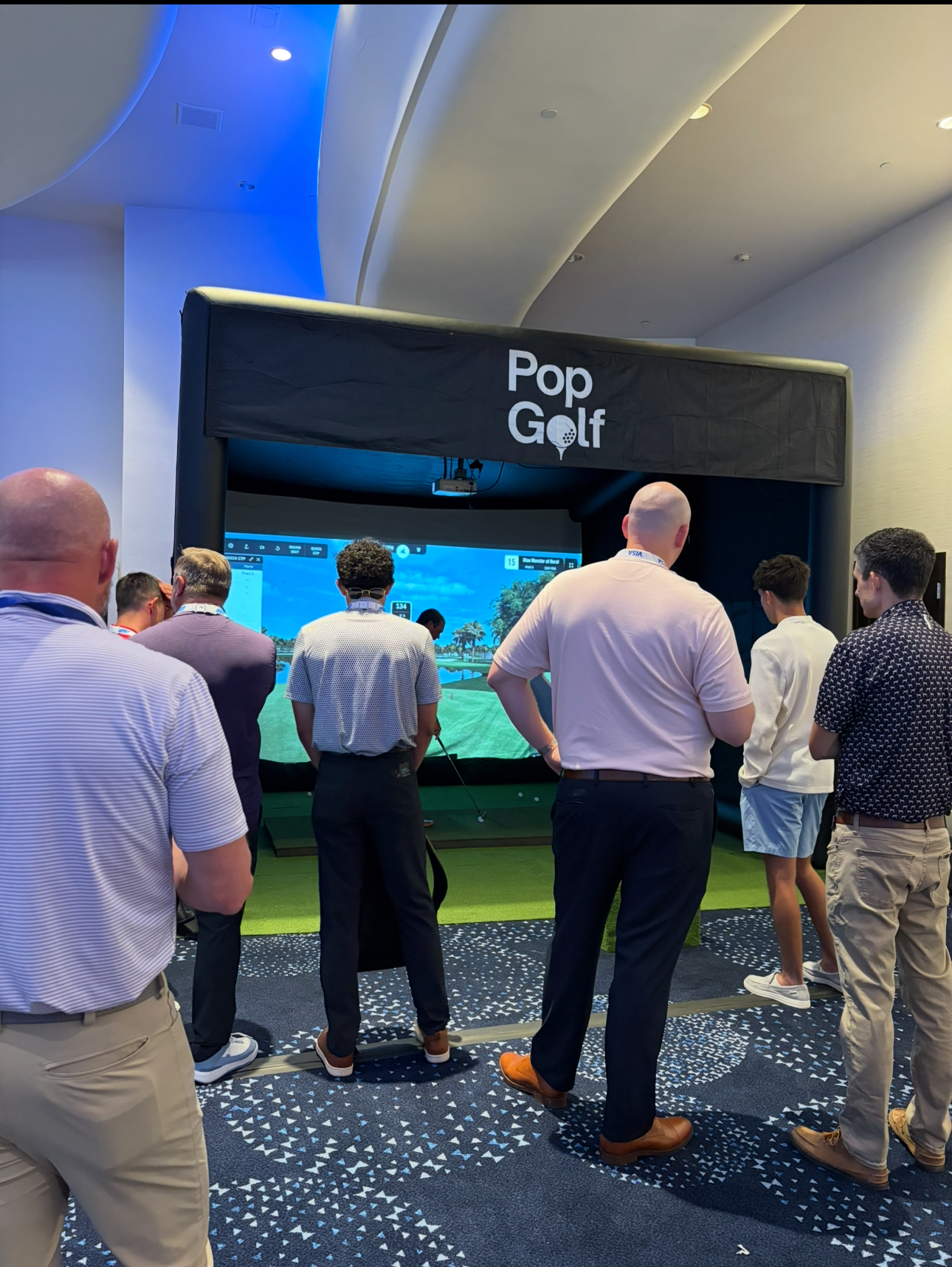 Attendees gathered around a PopGolf simulator during a conference at the Fontainebleau in Miami Beach.