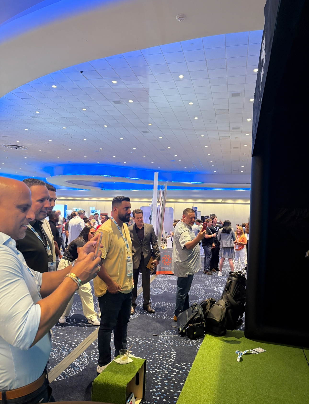 Conference attendees gathered around the PopGolf simulator at the Fontainebleau