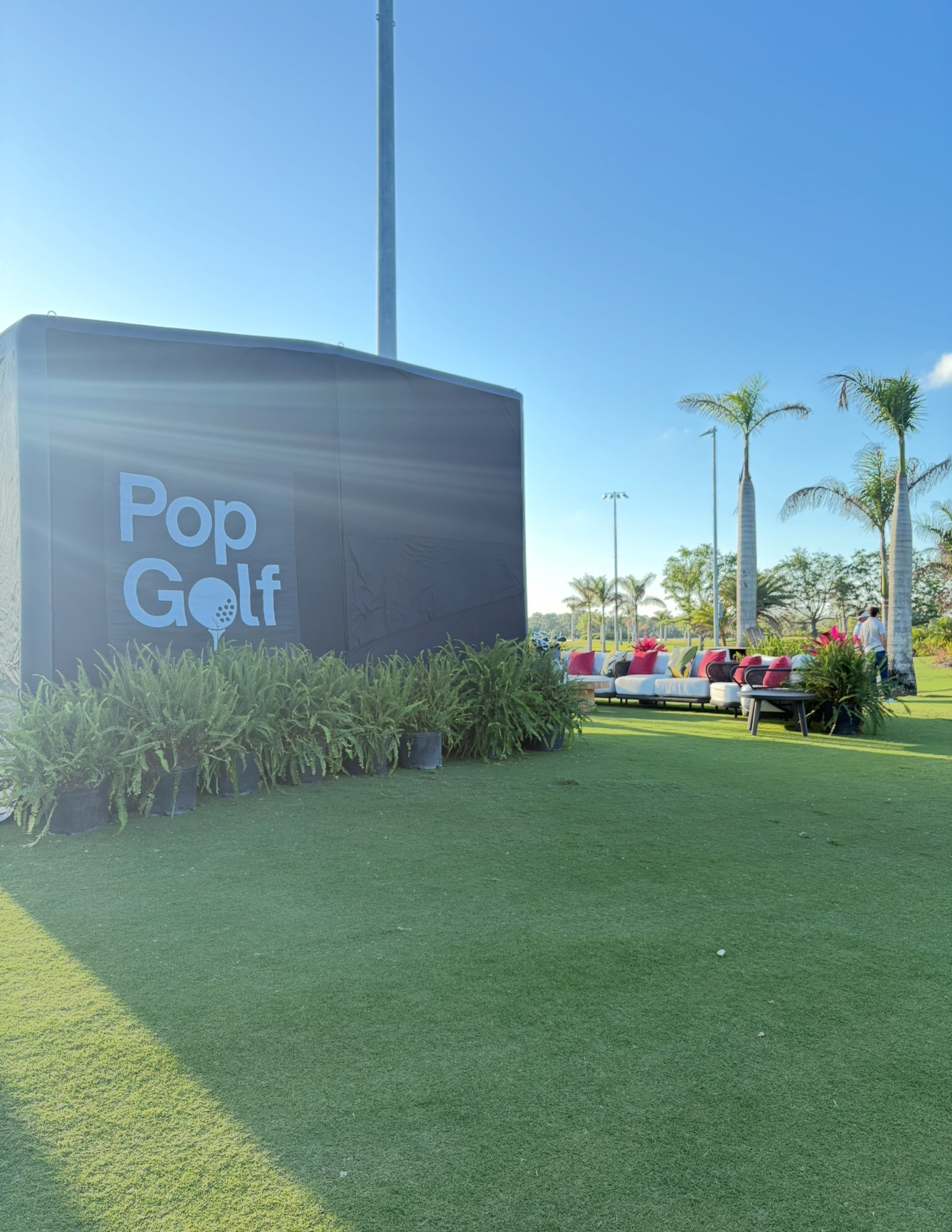 PopGolf simulator set up on a resort lawn for a corporate offsite with lounge seating and palm trees
